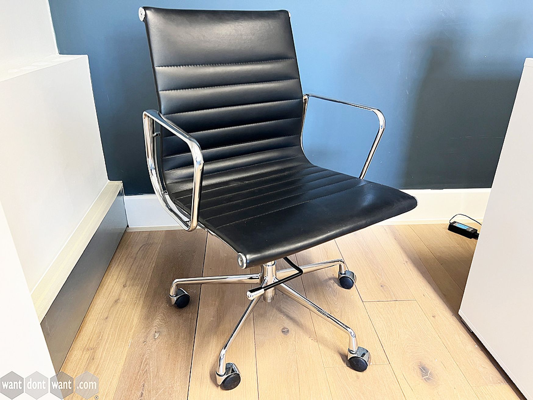 Used Eames style meeting chairs upholstered in black hide with chrome arms and base.
