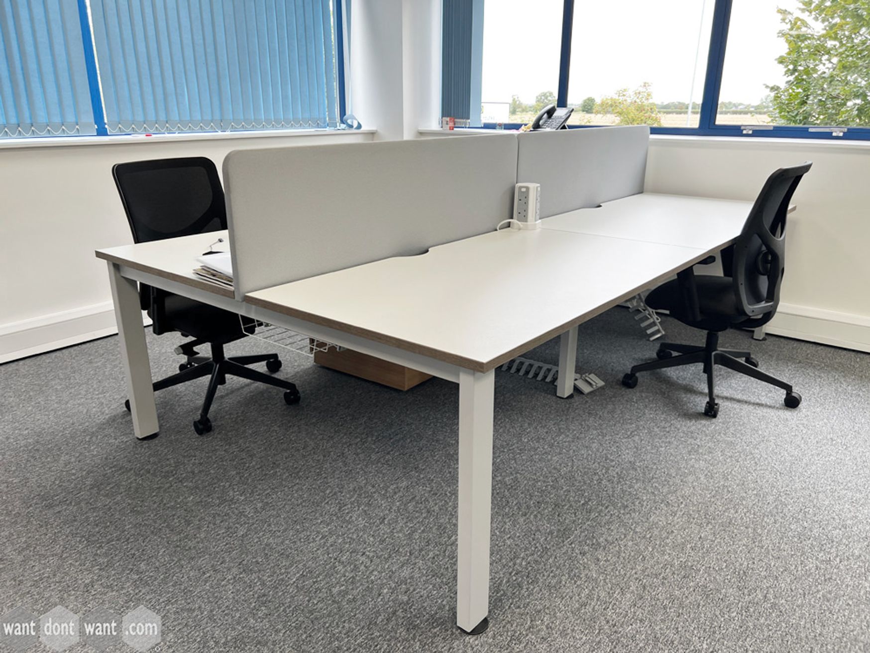 A used 4-person white bench desk with each desk position measuring 1400mm wide. 