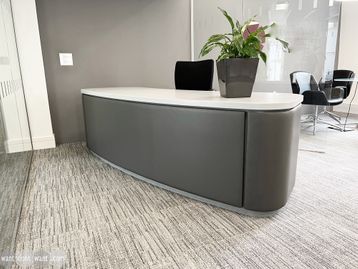 Magnificent used reception desk with 'Corian' curved top and leather upholstered side panels.